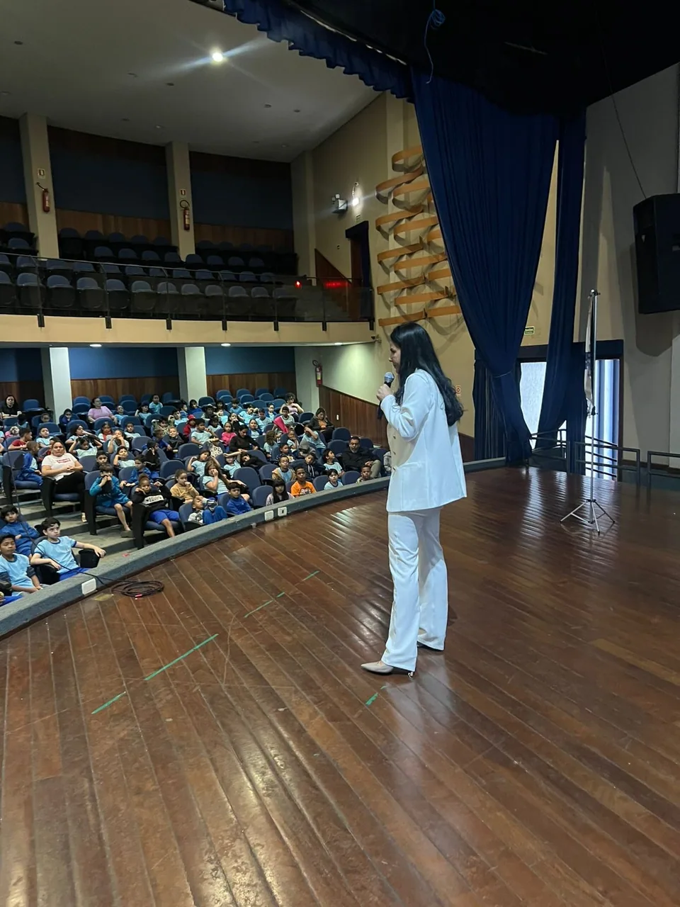 Dra. Genaina Morais falando ao público em auditório