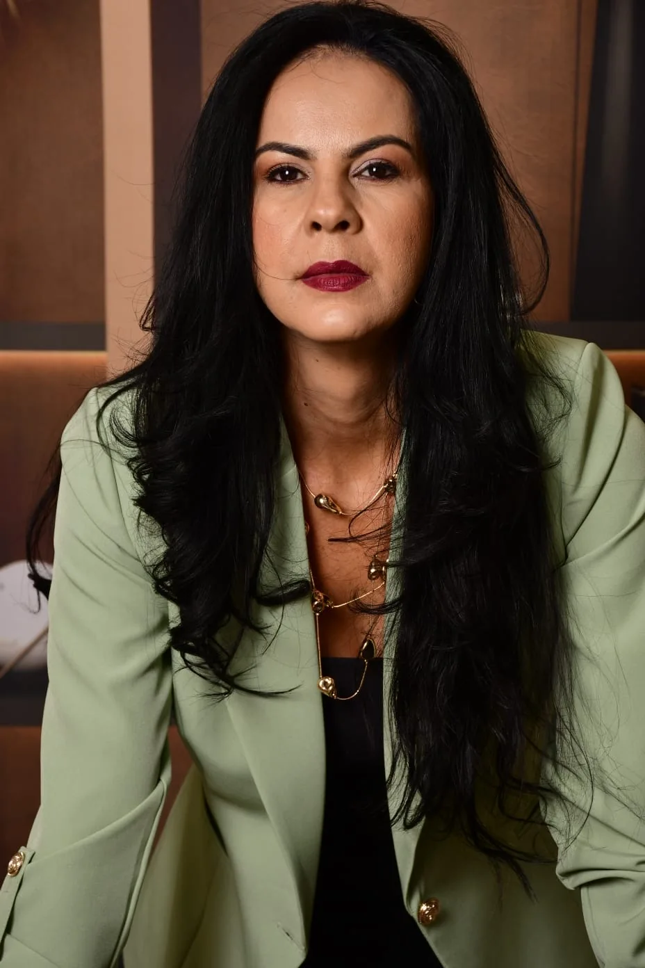 Dra. Genaina Morais em retrato profissional, com blazer verde