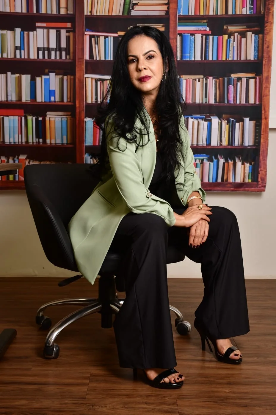 Dra. Genaina Morais sentada diante de uma estante de livros